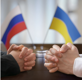 Ukraine and Russia Flag at ta table with two sets of hands.