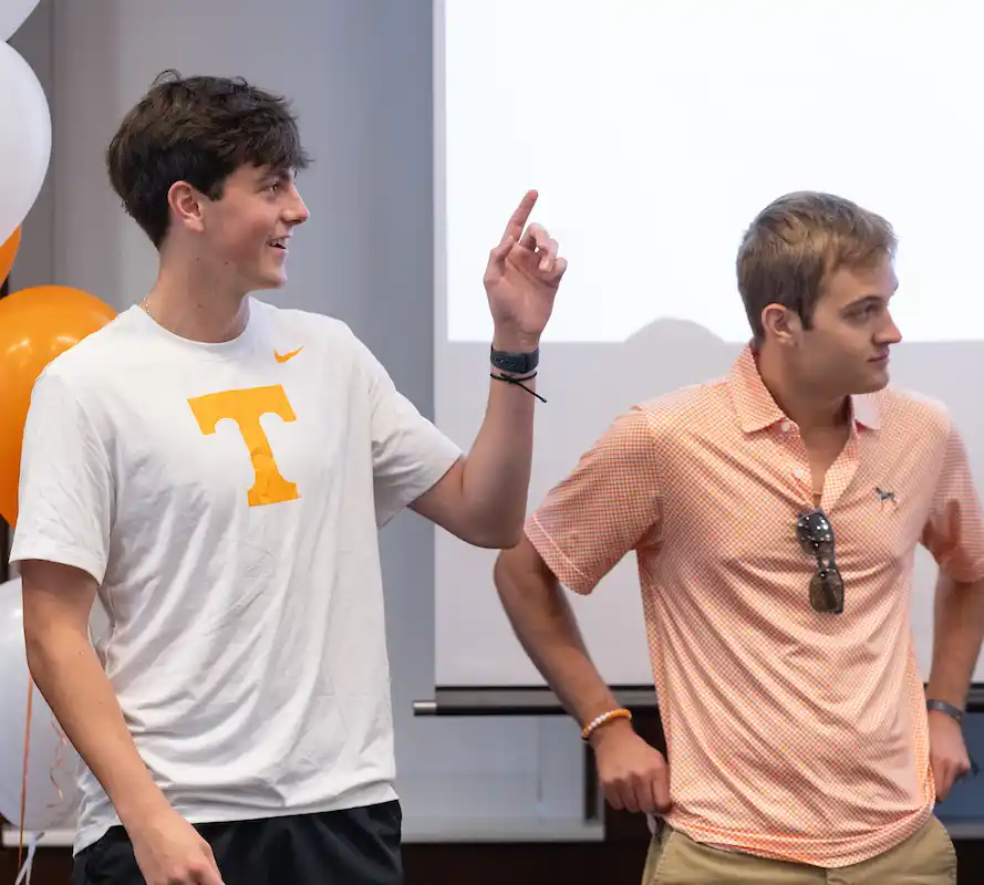 A group of two male students pointing and looking up at a screen that is not in view of the photo