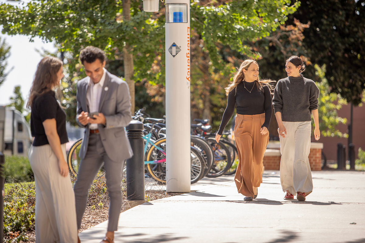 Photo of two students walking and talking on campus sidewalks